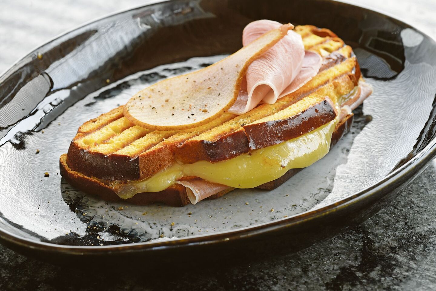 Dieser Croque trägt ganz die Handschrift des Kantons Freiburg. Die Cuchaule, das Freiburger Safranbrot, ist mit Vacherin Fribourgeois und Bénichonsenf gefüllt.