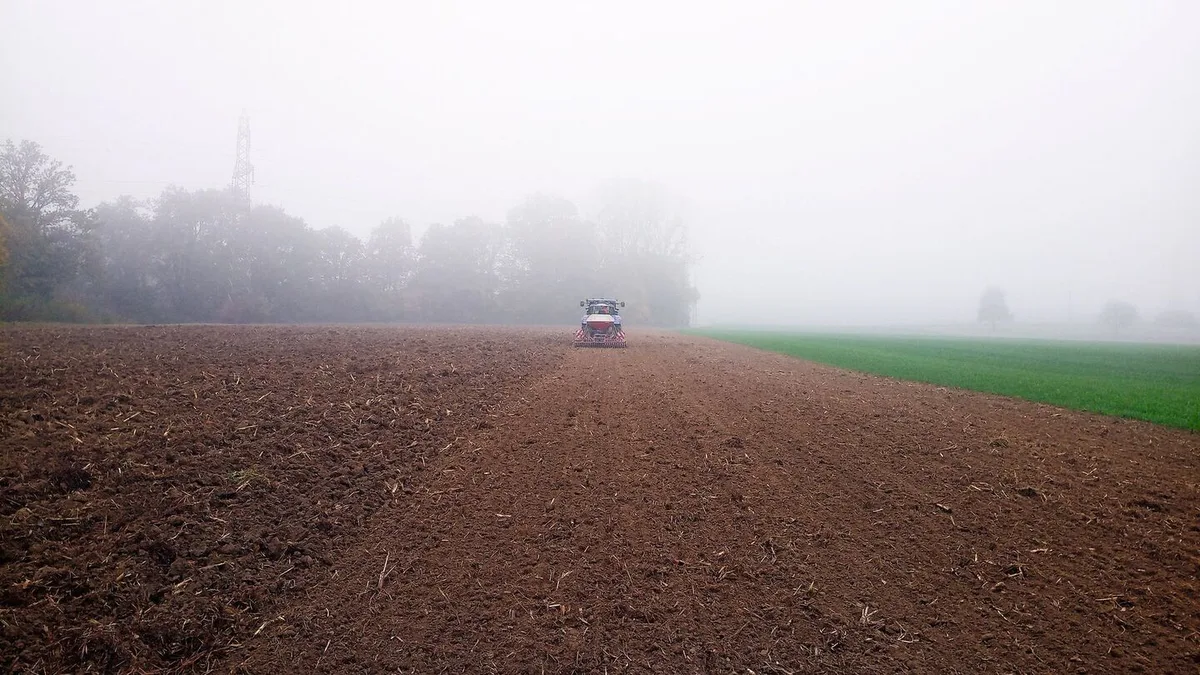 Traktor fährt mit der Sämaschine über das Feld.