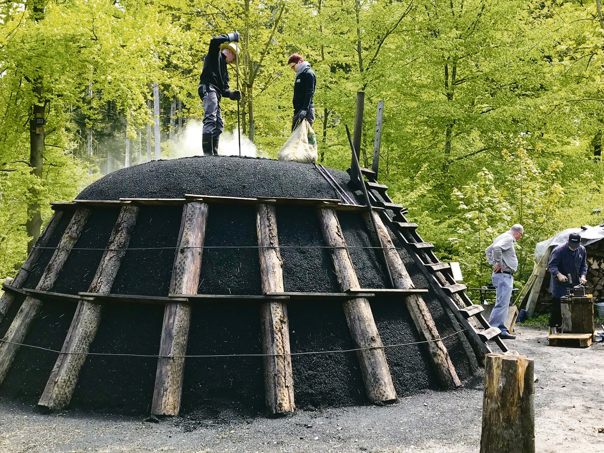 Einige Tage später qualmt der Kohlenmeiler und benötigt alle drei bis vier Stunden Pflege: Über Zuglöcher regulieren die Köhler die Luftzufuhr und damit den Verkohlungsprozess.