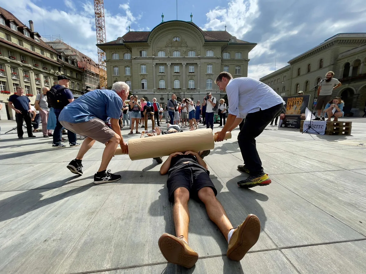 Bauern und Bäuerinnen werden von einer symbolischen «Walze der Grossverteiler» überrollt