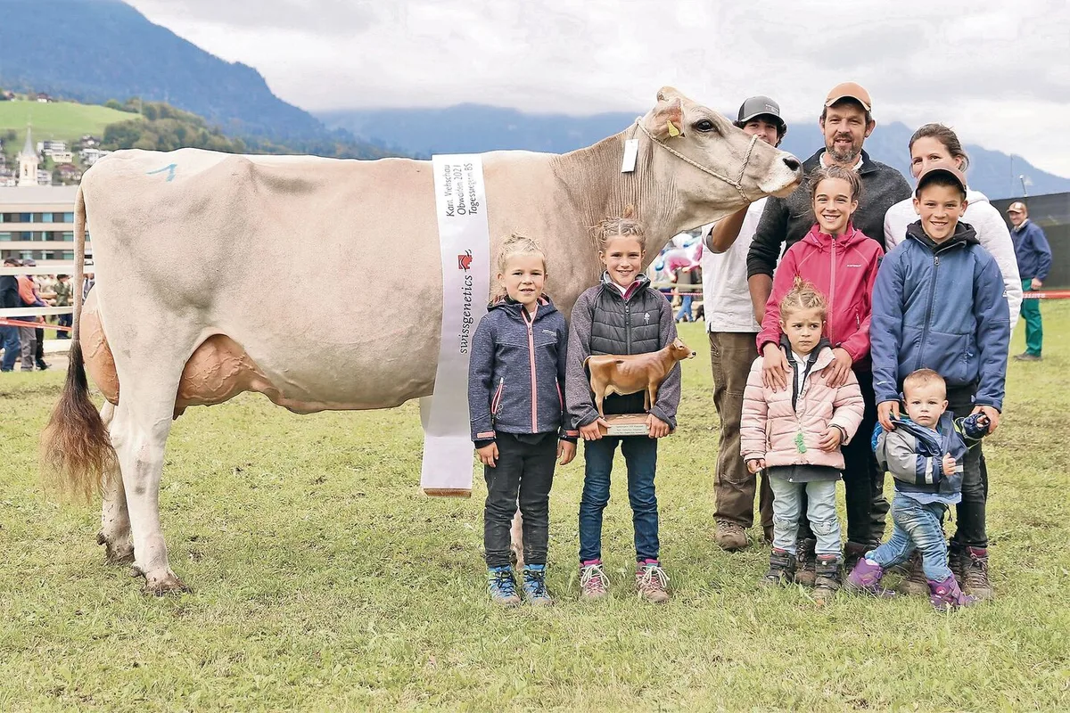 f0c2798d29d4850b4a7669e75d67695a8ea1fd39ec52703c5750d08a186b584d Familie Durrer und Braunviehkuh Jule, welche Miss Obwalden wurde. Geburtstagskind Mirjam trägt stolz den Siegerpreis in den Armen.