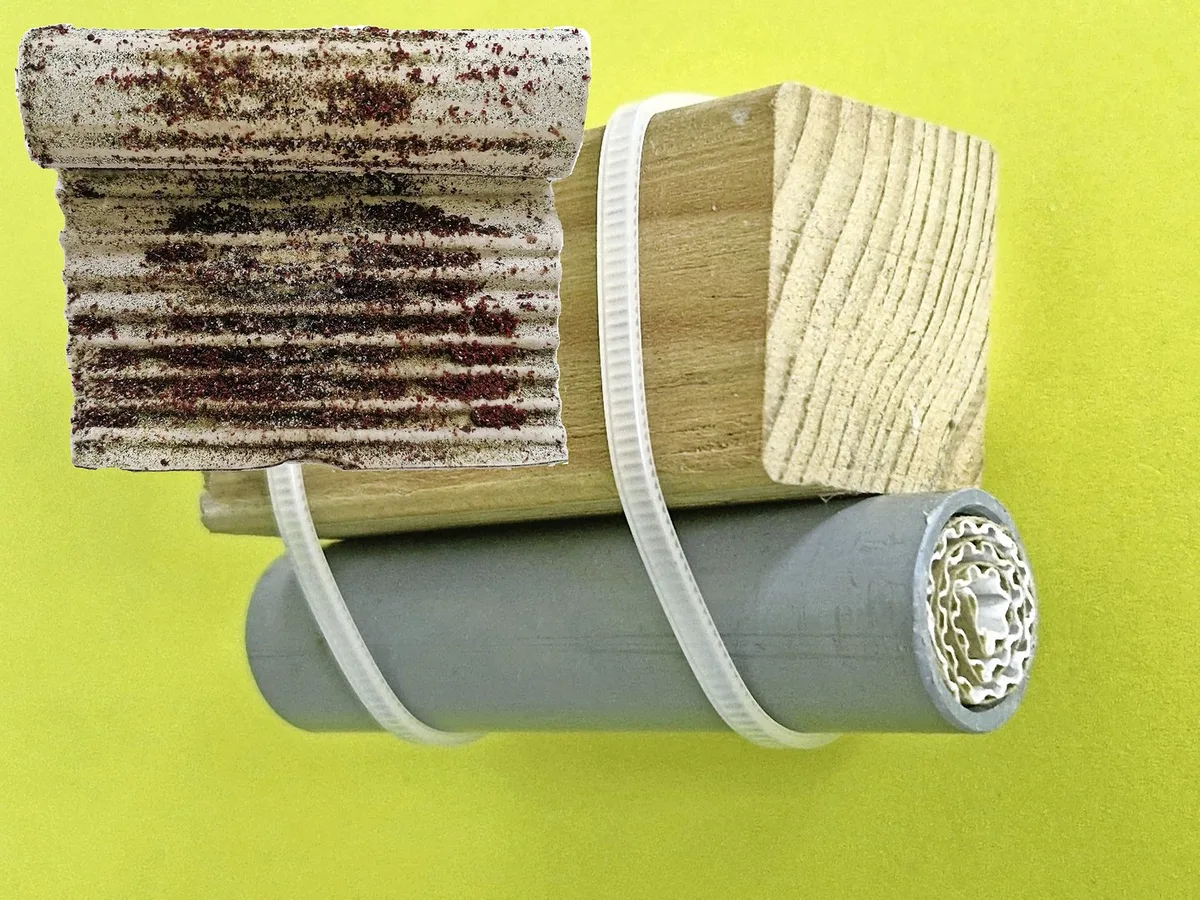 DG_25-06_SA_Milbenfalle_Gloor Milbenfalle aus Kunststoffrohr und aufgerolltem Wellkarton, unter einer Sitzstange befestigt. Zur Kontrolle wird das Papier herausgestossen und entrollt