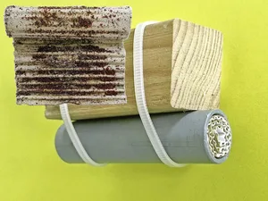 Milbenfalle aus Kunststoffrohr und aufgerolltem Wellkarton, unter einer Sitzstange befestigt. Zur Kontrolle wird das Papier herausgestossen und entrollt