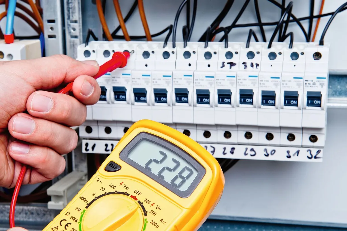 0f25b9ebaf9bd734b605f1417f37668bc18907672ca51badfe0865f5cb321560 Ein Multimeter wird bei einem Sicherungskasten benutzt, um die Stromspannung zu messen.