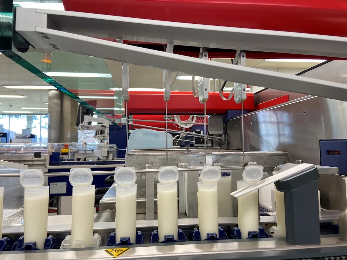 Milchprobe-Suisselab_KREBS-BAUZ Mehrere Ampullen mit Milchproben stehen auf dem Förderband im Labor von Suisselab.