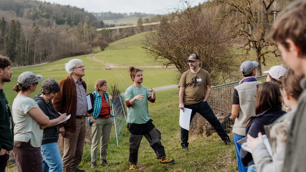 DG-2026-09-FoKo-ETH Patrick Spinelli (Mitte) und Martin Hartmann (rechts) führen an einem öffentlichen Anlass durch den Rebberg und präsentieren die Resultate der Bodenbeprobung.