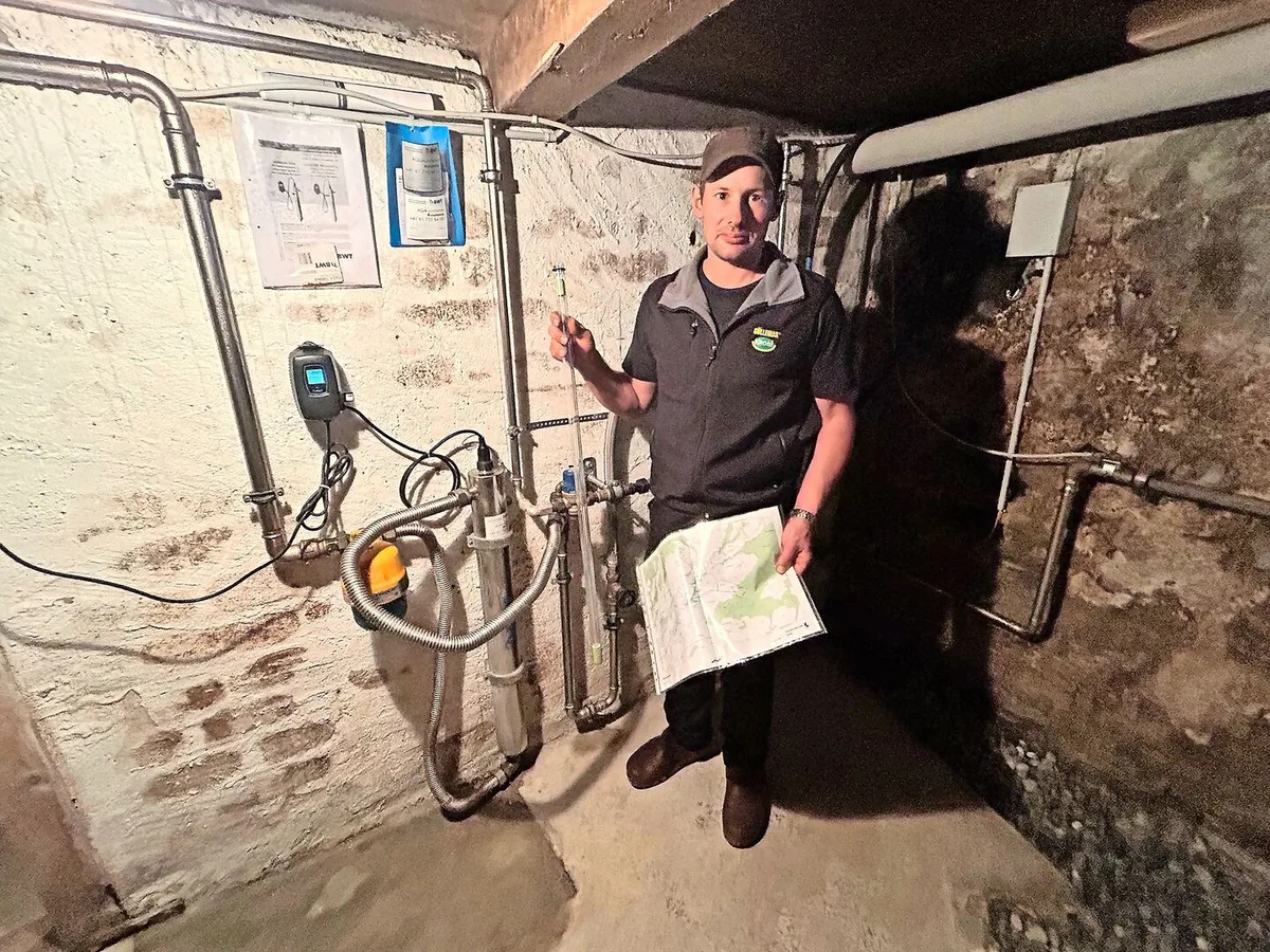 Werner Koller erklärt die Wasseraufbereitungsanlage im Keller seines Wohnhauses. In der rechten Hand hält er die UV-Lampe zur Reduzierung von Bakterien und Keimen.