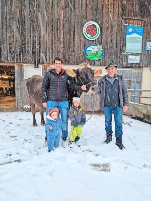 Drei Generationen und eine Ausnahmekuh: Mathias Jud mit den Töchtern Mara (l.) und Lea und sein Vater Wendelin. Die Braunviehkuh Ursi hat bereits über 127'000 kg Milch geleistet.