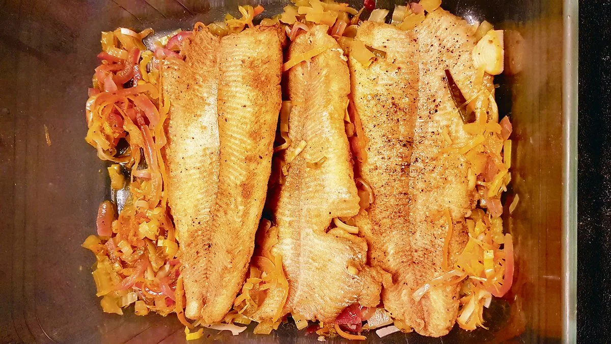 Angebratenen Fisch auf einen Teil des Gemüses legen.