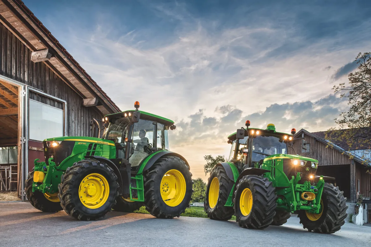 Zwei John Deere-Traktoren im Gegenlicht.