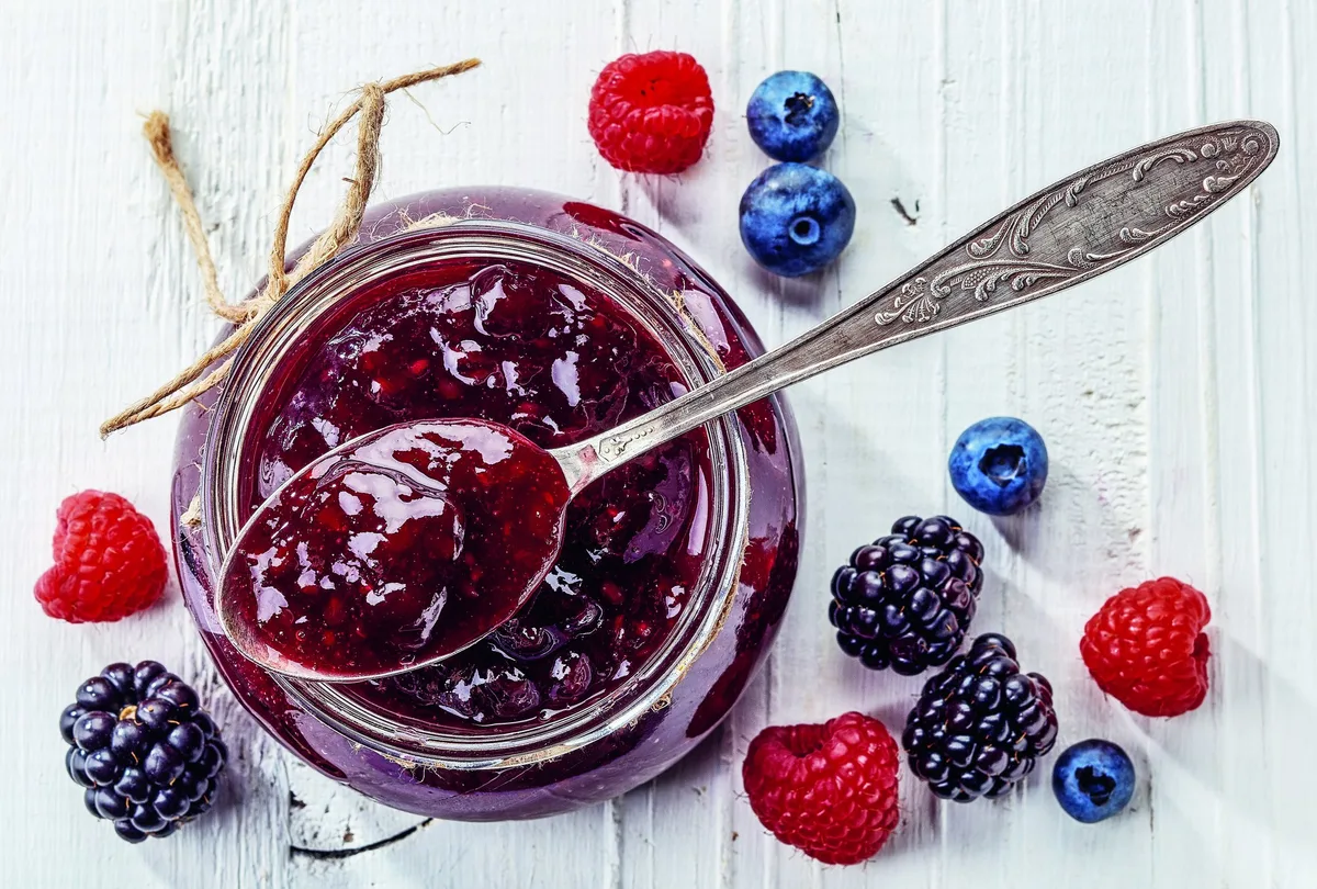 09_konfiture Himbeeren, Brombeeren und Heideleeren neben einem Glas Konfitüre.