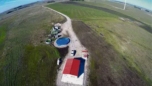 Wohnhaus, Container und Wasserreservoir sowie im Hintergrund die Linien mit den ersten Pekanbäumen.