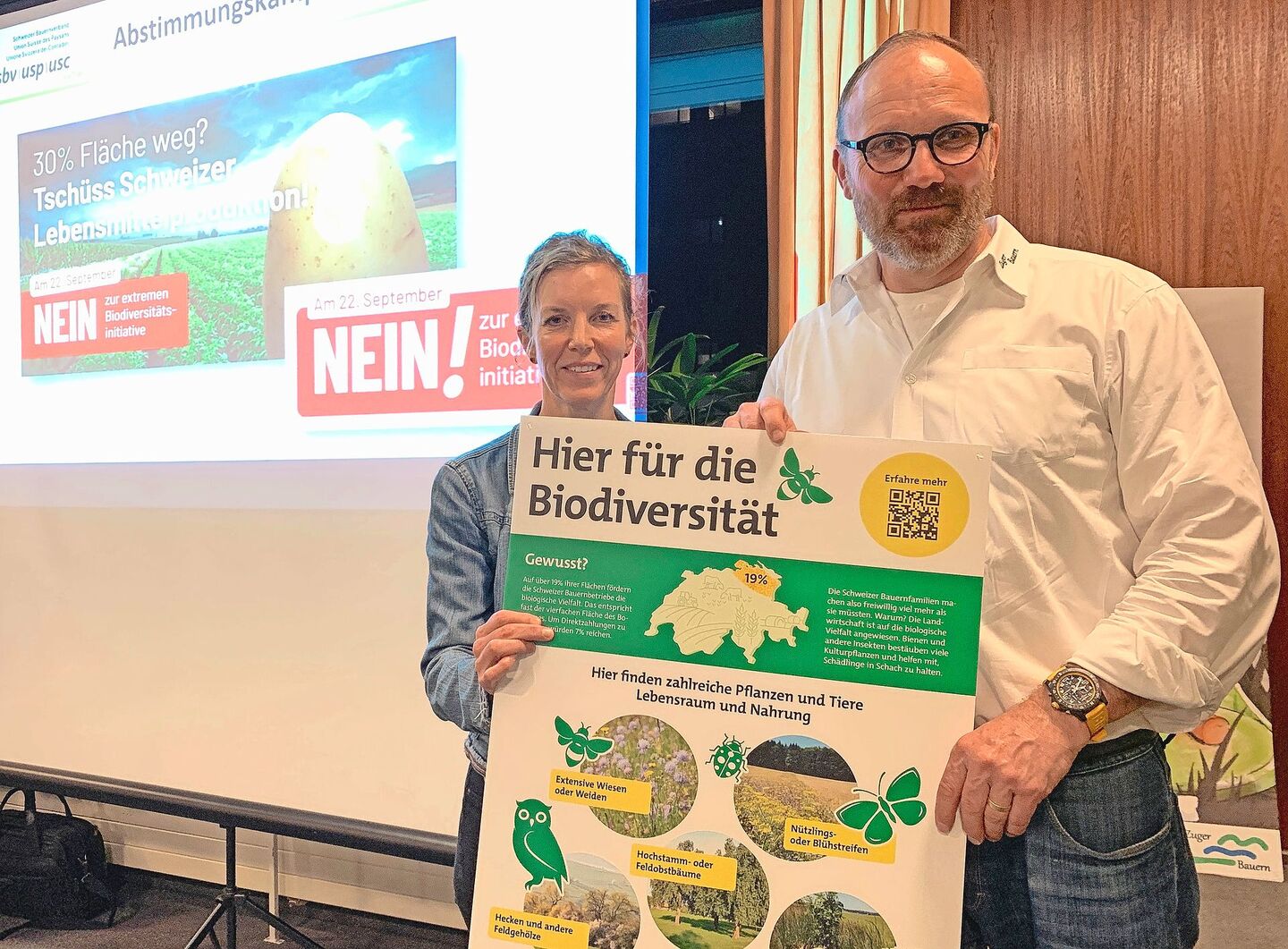 Thomas Rickenbacher und Sandra Helfenstein präsentieren das Plakat, dass auf Höfen auf die vielen bereits bestehenden Biodiversitäts-Förderflächen hinweisen soll.