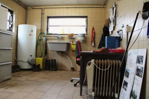 Die Arbeitsschuhe trocknen in dieser einfachen Schmutzschleuse unter einem Trog, ein Elektro-Ofen spendet etwas Wärme.Der Nassraum wird auch als Abstellraum genutzt – als Arbeitsplatz für andere Tätigkeiten eignet er sich hingegen nicht.