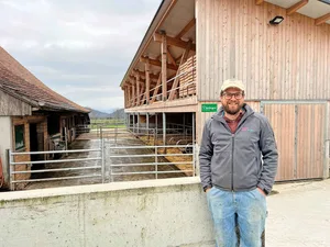 Christof Bühler vor dem Mutterkuhstall (vorne) und Pferdestall (hinten). Im alten Stall wurde nur innen investiert, und zwar in Liegeboxen, Fressachse und Abkalbebox.