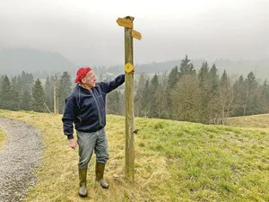 Willi Trüb von der Haselegg, Entlebuch, zeigt auf die Richtungsschilder für den Wanderweg Richtung Schwarzenberg. Nicht wenige Wandernde würden die aber nicht beachten und auf dem Schotterweg links weiterlaufen.