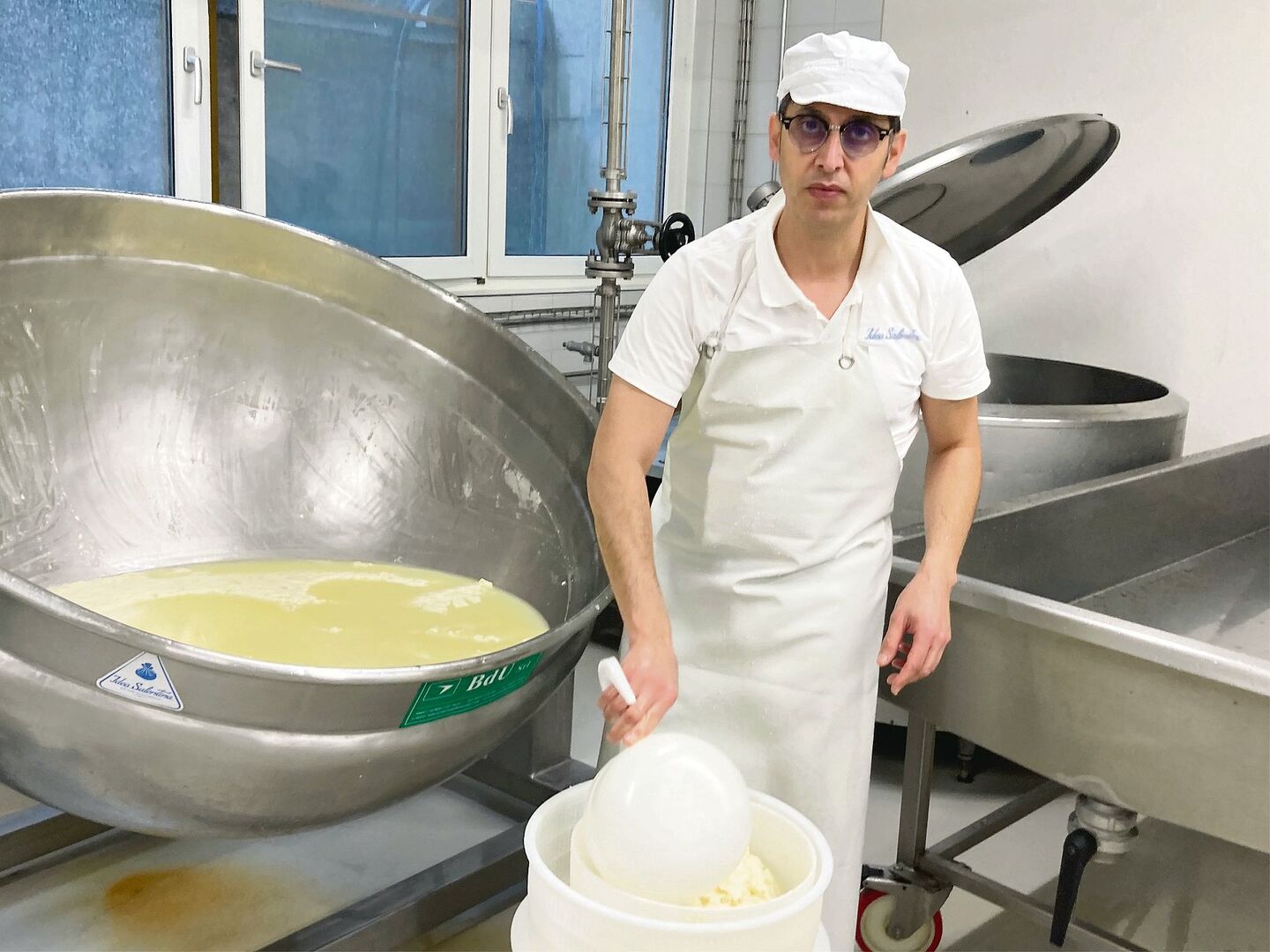 Mozzarella-Herstellung ist hier Handarbeit: Roberto De Matteis entnimmt dem Bottich den Käsebruch, um ihn anschliessend zu rühren, zu kneten und auseinander zu ziehen.