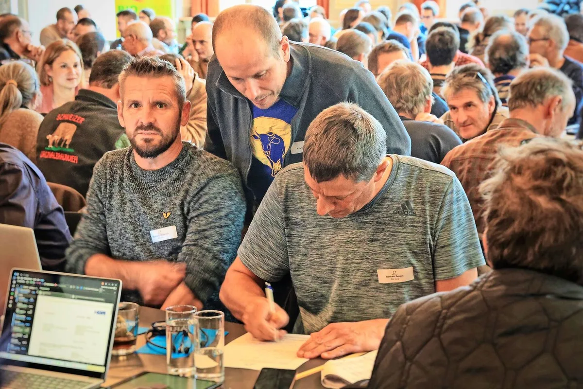 ec66eca7dc8ca5b3cf42b90c724e8eef5f3f7222e928d75ba1fe1125539424b4 Reicht spontan einen Antrag ein: Romain Beuret von Bio Jura (mit Blatt und Stift), hinter ihm steht François Devenoge von Bio Vaud, links im Bild Bertrand Wüthrich von Bio Jura.