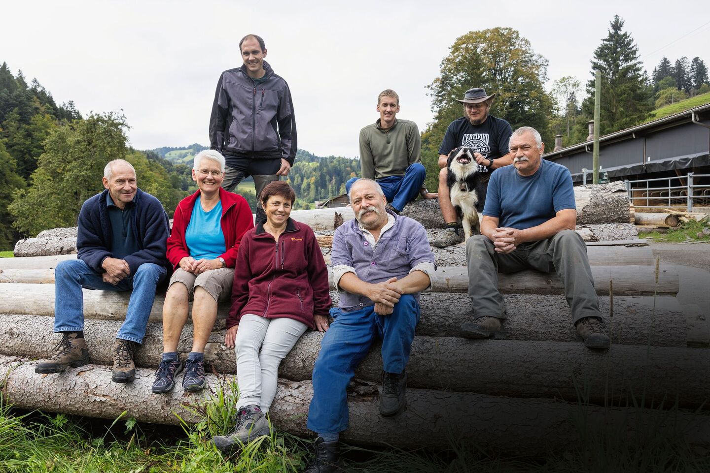 Gruppenbild der drei Familien, wie sie auf Holzstämmen sitzen.