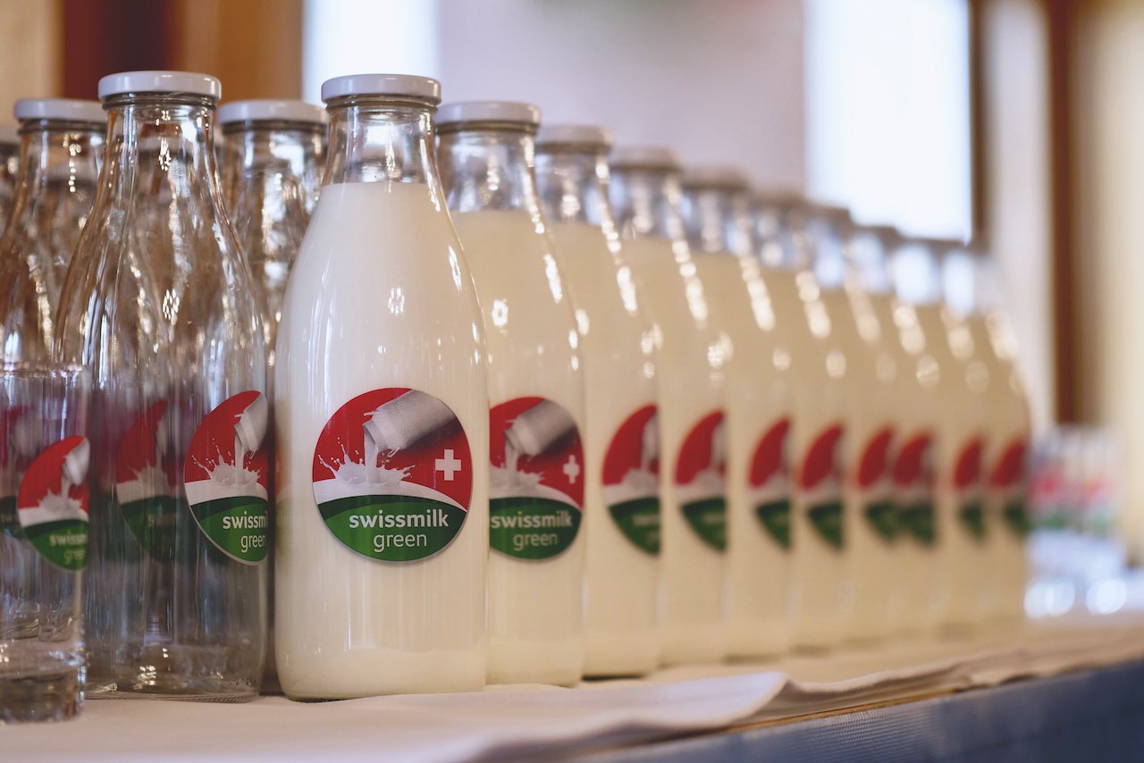 Eine Reihe Milchflaschen mit der Marke «swissmilk green».