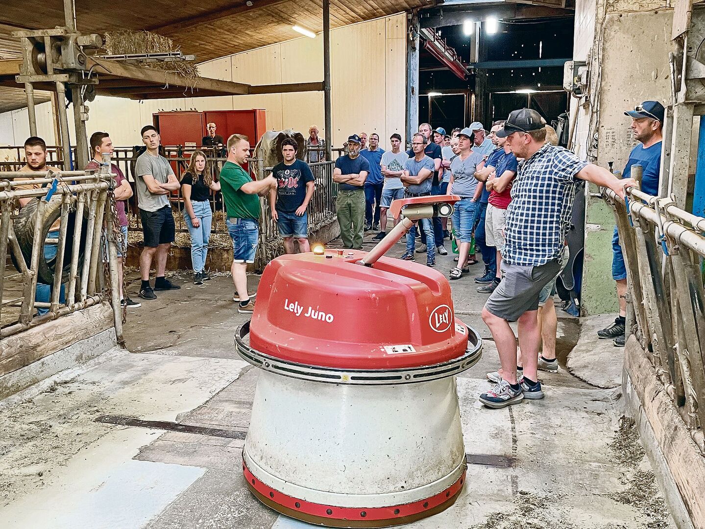 Der automatische Futterschieber «Wäutu» lässt sich von den Besuchenden auf dem Sonnhaldenhof nicht stören, während Betriebsleiter Marc Grüter (im grünen T-Shirt) erklärt.
