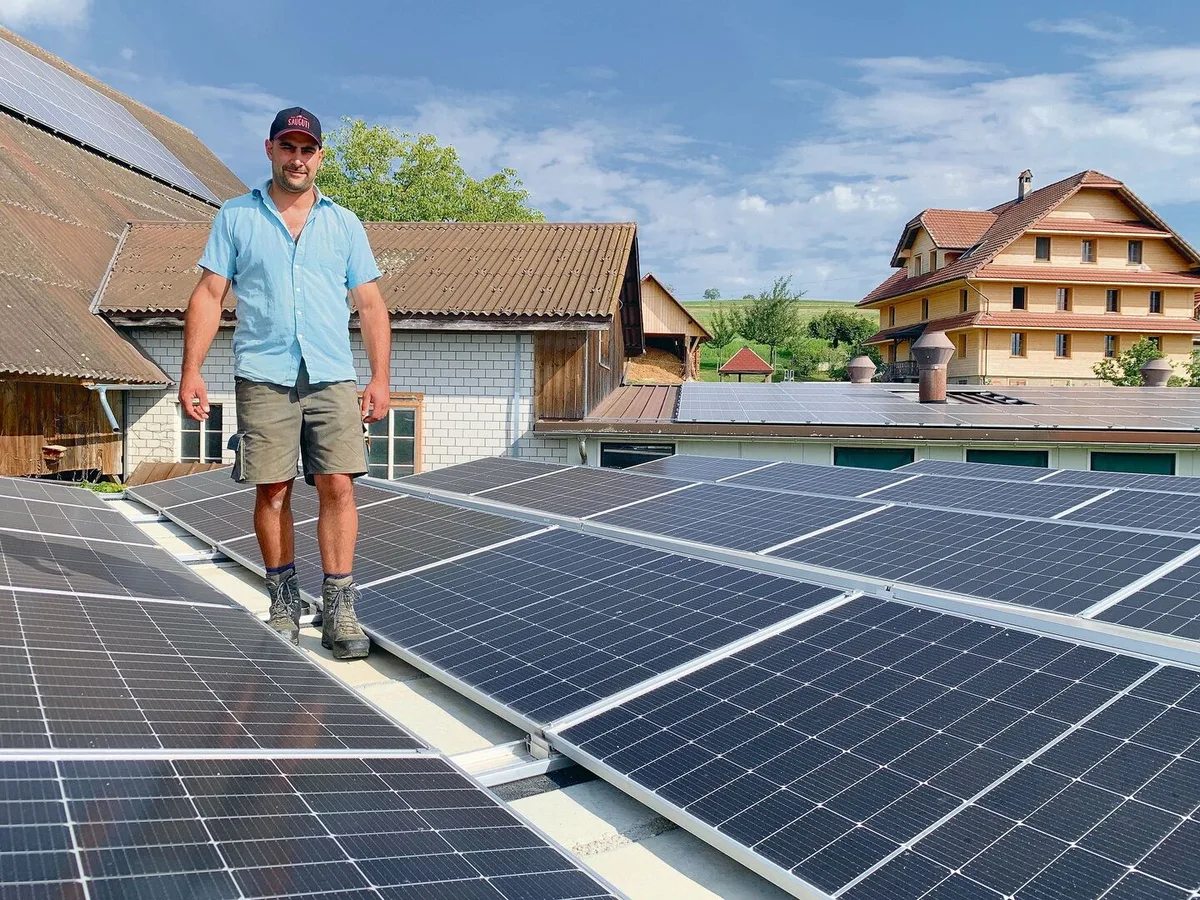 e39cf350c6f3ee45e8668129b1db0947c8ff4a2c5e2ae30c48ea73391a7e420f Adrian Bucheli auf dem mit PV-Modulen belegten überdachten Güllesilo. Solarstrom, auch für das sanierte Bauernhaus hinten, produziert er auch an der Scheunenfassade, auf dem Scheunendach (l.) und über dem Schweinestall (hinten).
