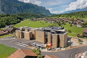 Das «Bretterhotel» mit der fünf Meter hohen Holzkuh in Hofstetten bei Brienz BE aus der Vogelperspektive. Am Waldrand die Museumsstrasse, die direkt zum Kurszentrum Ballenberg führt.
