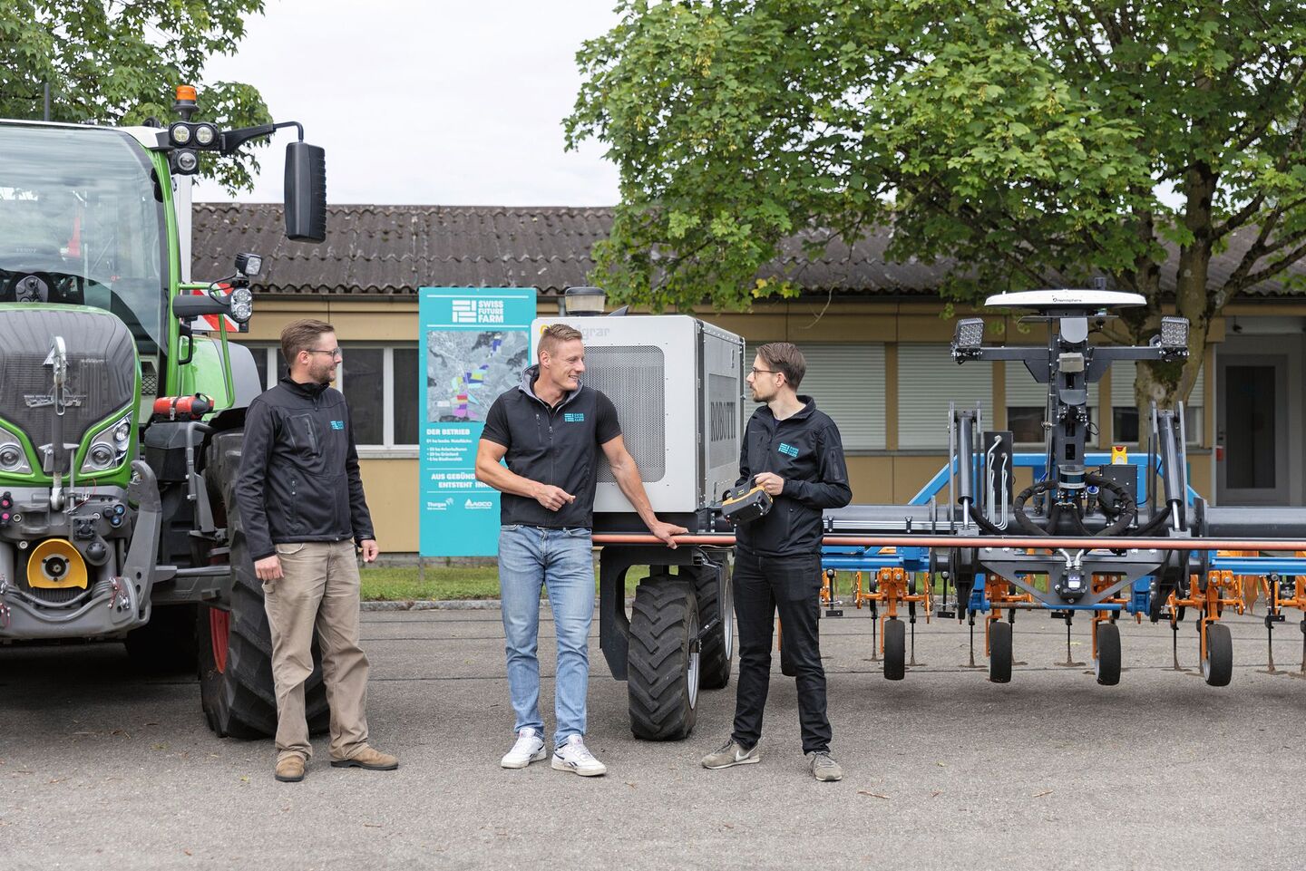 Nils Zehner (AGCO) Roman Gambirasio (GVS)und Florian Abt (Arenenberg) stehen vor einem Fendt-Traktor sowie einem Feldroboter.