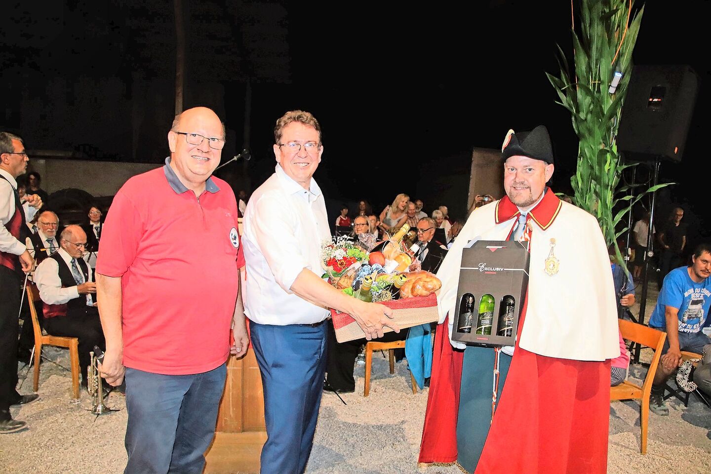 Urs Stähli, Präsident des Schützenvereins Ossingen, dankt Bundesrat Albert Rösti mit einem grossen Geschenkkorb und drei Flaschen Wein, die sein Weibel Carlo Pfister für ihn in der Hand hält (v. l.).