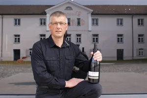 Der Rebmeister Moritz Villiger posiert mit dem Bündner Regierungswein, der künftig ebenfalls am Plantahof in Bioqualität produziert werden wird. (Bild zVg)