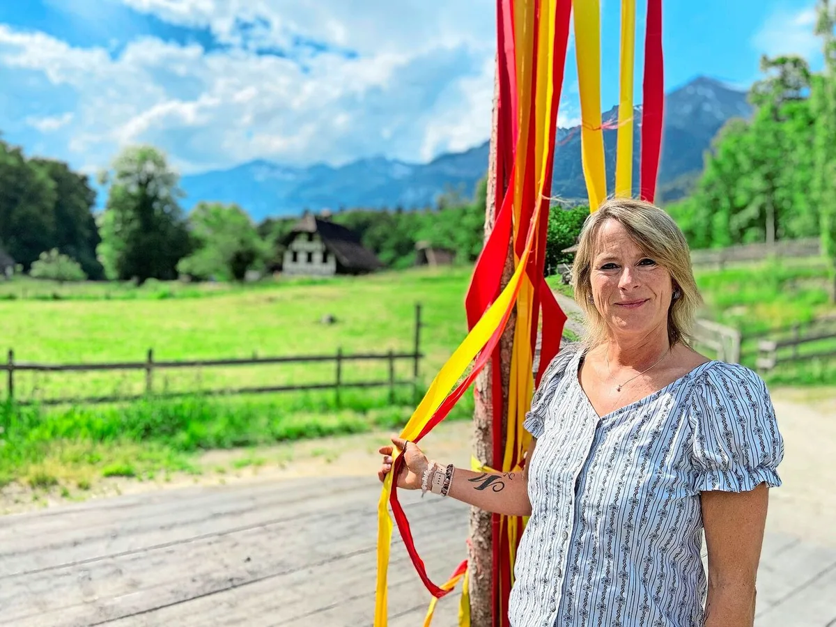 f78b64604395523a15141a2019143c4ba67c6a681b57fefbd8ae2a3d07468e46 Olivia Wyss beim Maibaum auf dem Dorfplatz, wo das Theater spielt. Die ganze Inszenierung ist mitten in die Landschaft des Ballenbergs integriert.
