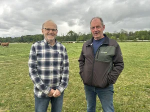 Ueli Heeb und Hans Eschenmoser bestreiten den Posten «Landwirtschaft» am Tag der Thur. Hinter den weidenden Kühen ist der Thurdamm zu sehen.