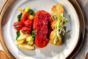 Als vegetarische Hauptspeise serviert Lorena Röösli Hackbraten aus Schweizer Kidneybohnen mit Tomatensauce, Serviettenknödel, Petersilienpüree, Kohlrabi, Cherrytomaten, Kürbisschnitze und Lauchstroh.