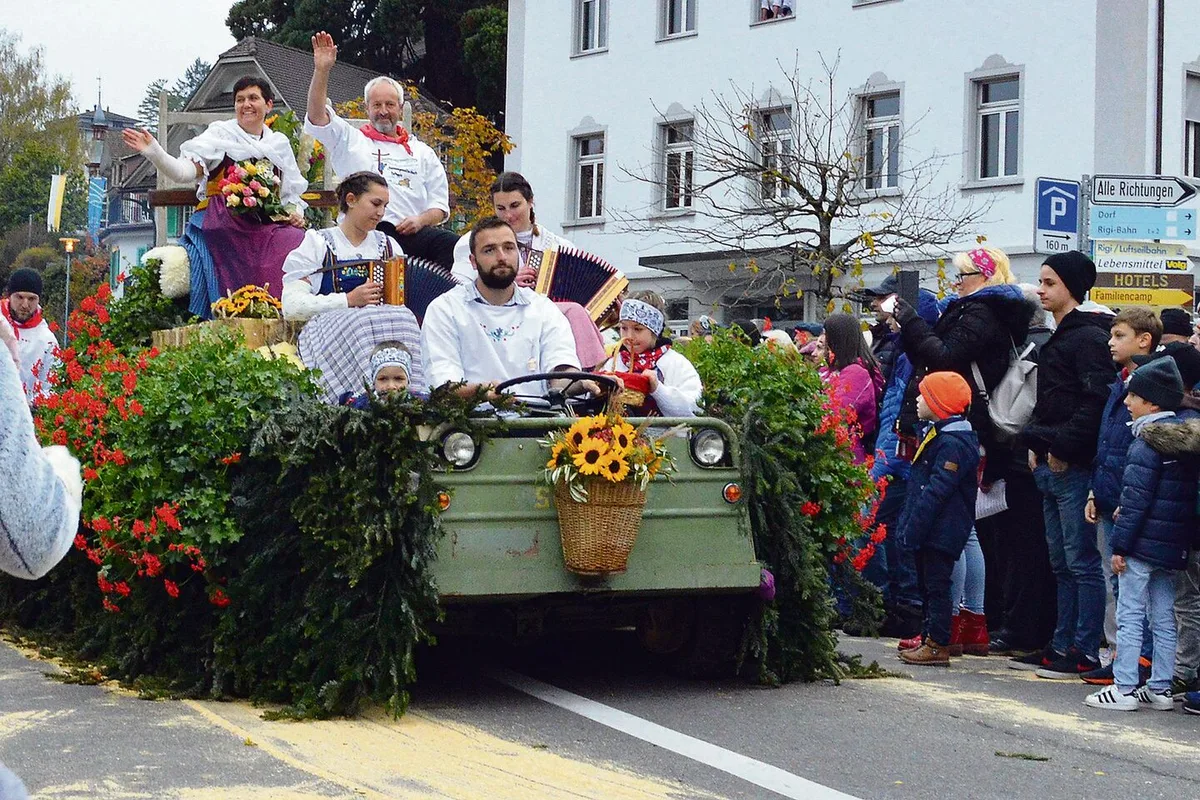 Sennenammann Albert Gössi und seine Frau Paula grüssen von einem prächtig geschmückten Umzugswagen.
