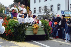 Sennenammann Albert Gössi und seine Frau Paula grüssen von einem prächtig geschmückten Umzugswagen.