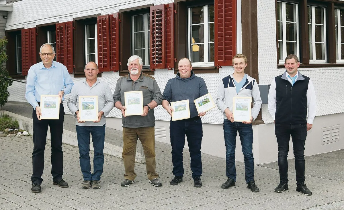 f80302f19651cadf9989816f22b18db376f29ca8fd8f11b31d66d55e9123f7fb Vier der anwesenden Züchter der 100 000er-Kühe mit Braunvieh-Schweiz-Direktor Lucas Casanova (l.) und Cyrill Gauch (r.).