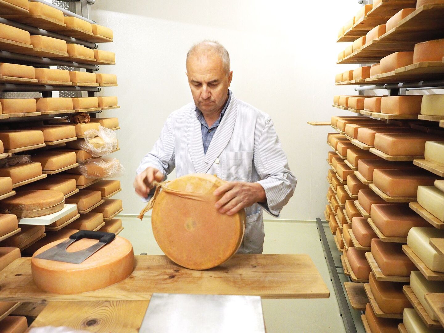 Auspacken eines Raclette-Käses aus der biologisch abbaubaren Hülle im Keller der Küssnachter Dorfkäserei.