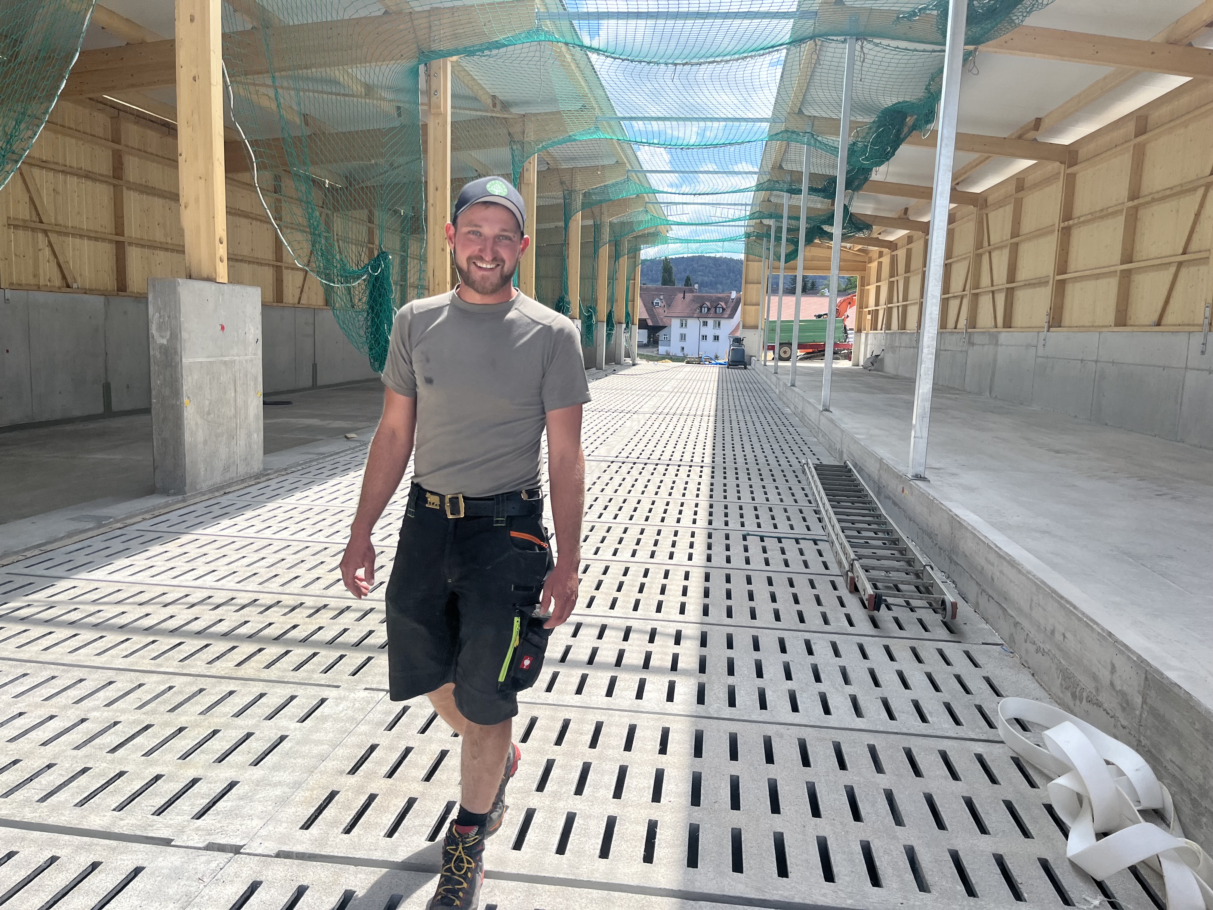 Marc Miesch im neuen Laufstall auf dem Betrieb in Wittinsburg: Der Gitterrost unter seinen Füssen wird künftig mit gespeichertem Regenwasser bewässert, um Ammoniak-Emissionen zu senken.