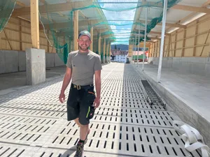 Marc Miesch im neuen Laufstall auf dem Betrieb in Wittinsburg: Der Gitterrost unter seinen Füssen wird künftig mit gespeichertem Regenwasser bewässert, um Ammoniak-Emissionen zu senken.