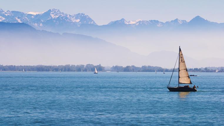 Bodensee mit Segelboot und Blick auf die Alpen