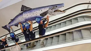 Für den Lachs braucht es weitere Fischtreppen. WWF-Aktivisten mit einem Riesenlachs auf der Rolltreppe des Basler Congresszentrums.