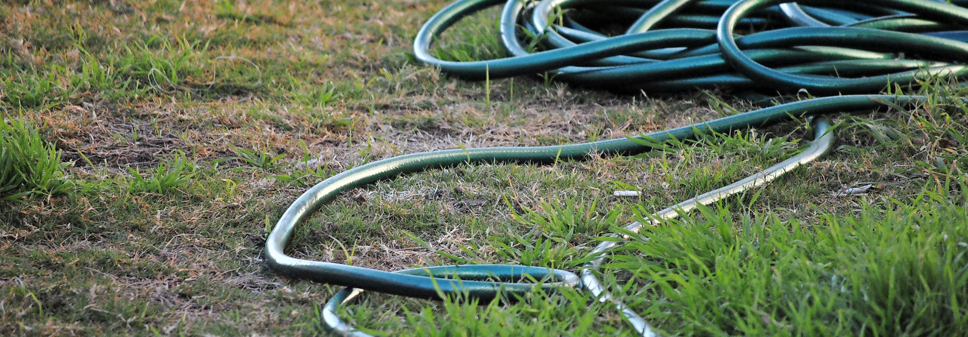 Gartenschlauch auf trockenem Rasen