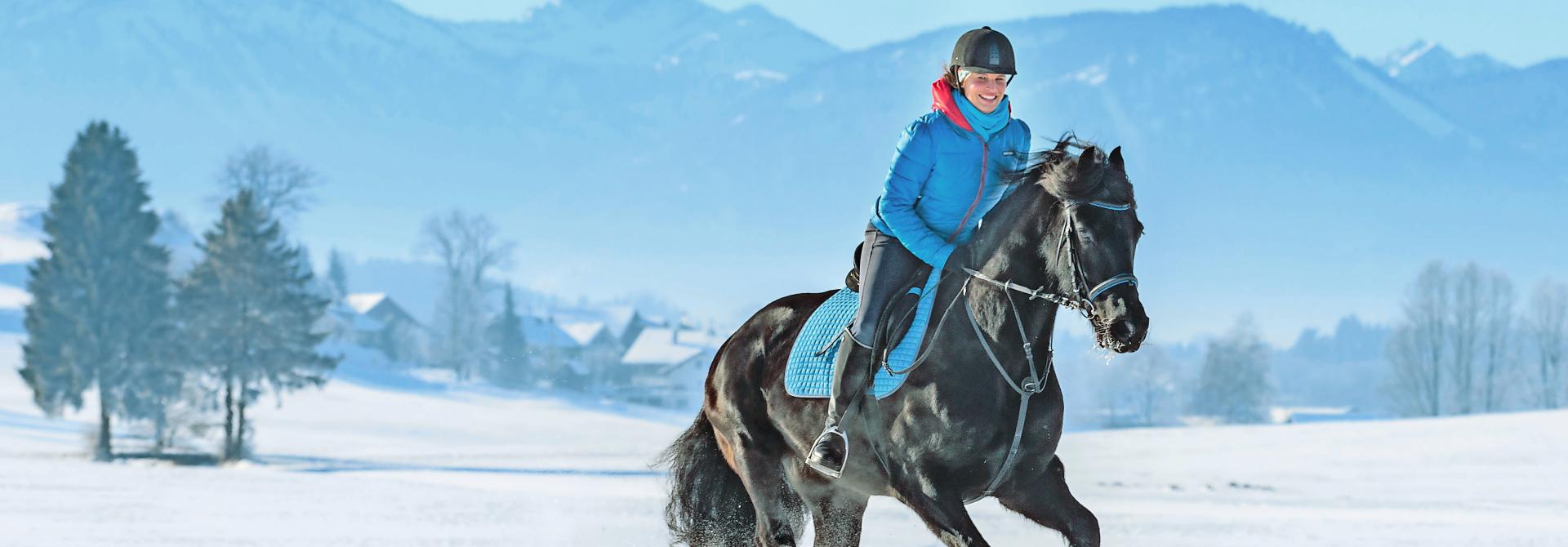 Frau reitet durch den Schnee