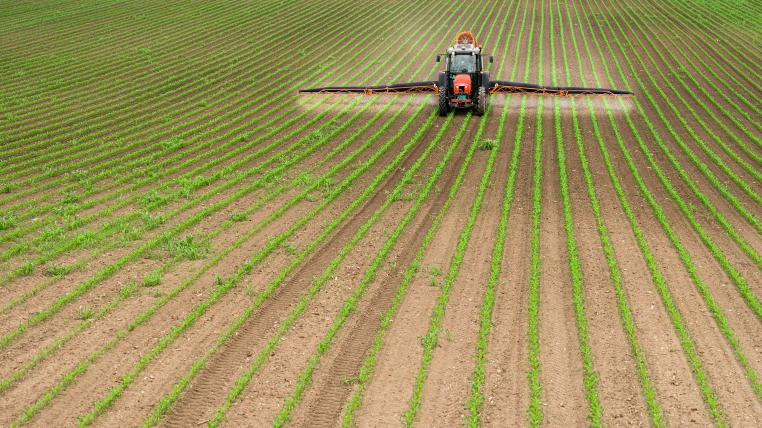 Traktor spritzt Pestizide auf Feld
