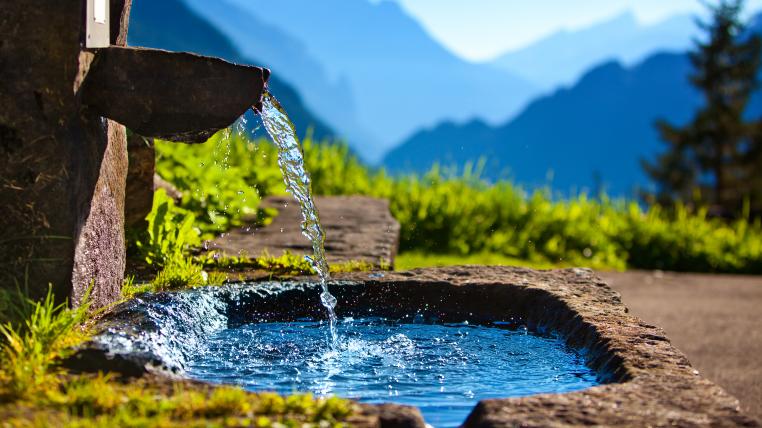 Klares Wasser kommt aus einem Brunne in den Bergen