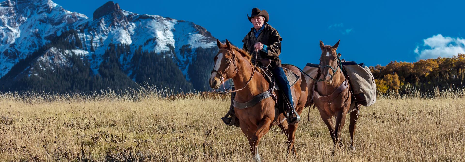 Cowboy reitet mit Handpferd